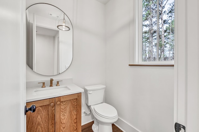 half bathroom featuring toilet, vanity, and baseboards
