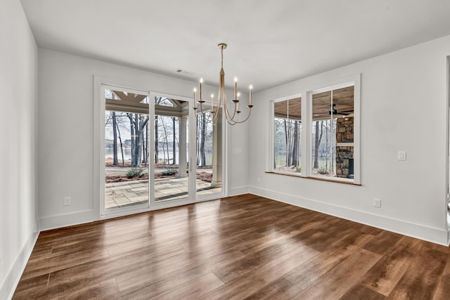 unfurnished dining area featuring healthy amount of natural light, dark wood-type flooring, and a chandelier