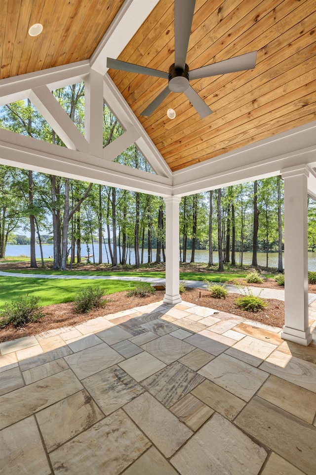 view of patio / terrace with a water view, ceiling fan, and view of scattered trees