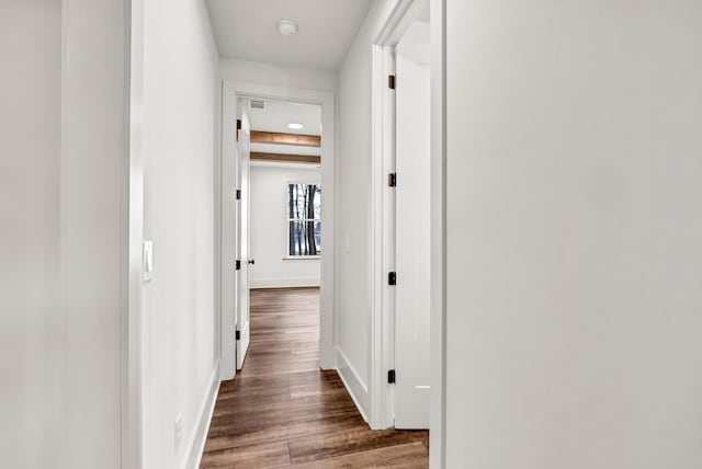 corridor with dark wood-style floors and baseboards