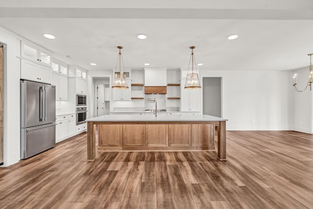 kitchen featuring appliances with stainless steel finishes, a chandelier, light countertops, dark wood finished floors, and a spacious island
