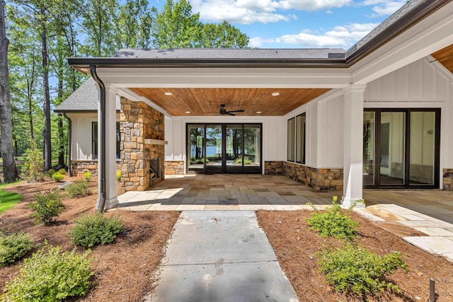 property entrance featuring stone siding, a ceiling fan, board and batten siding, and a shingled roof