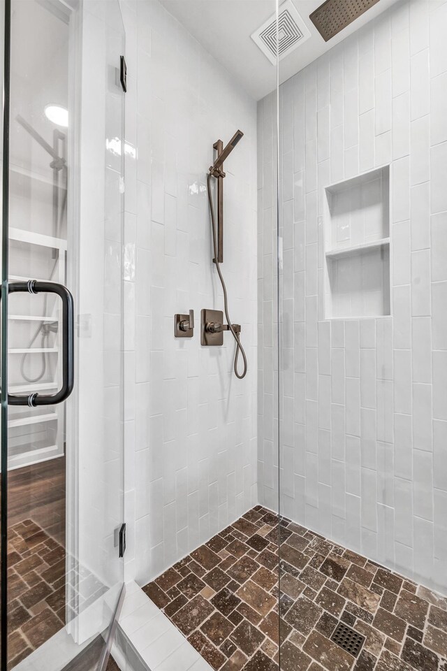 bathroom featuring a tile shower and brick flooring