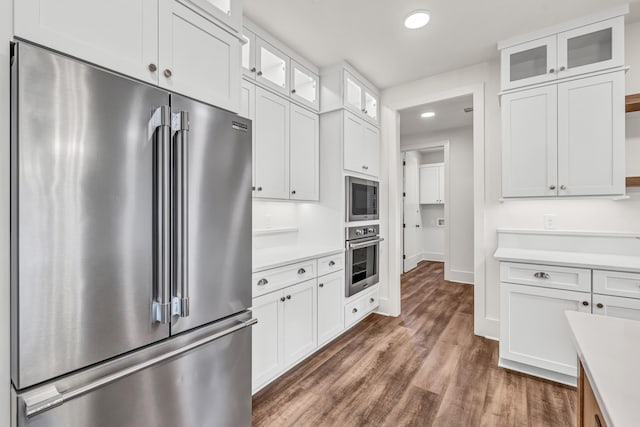 kitchen with stainless steel appliances, light countertops, recessed lighting, white cabinetry, and dark wood-type flooring