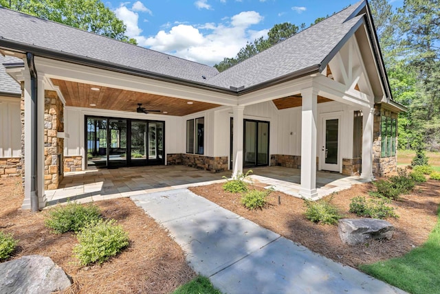 back of house with stone siding, a shingled roof, and a ceiling fan