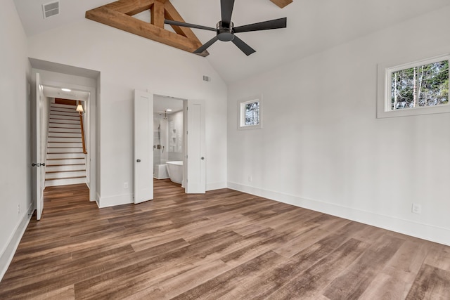 unfurnished bedroom featuring baseboards, wood finished floors, high vaulted ceiling, ensuite bathroom, and ceiling fan