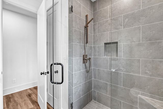 bathroom with a stall shower, wood finished floors, and baseboards
