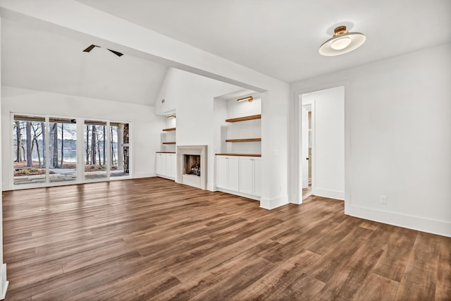 unfurnished living room with wood finished floors, baseboards, a fireplace, vaulted ceiling, and built in shelves