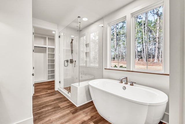 bathroom with plenty of natural light, a shower stall, a soaking tub, and wood finished floors