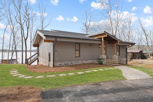 view of front of home featuring a front lawn and a shingled roof