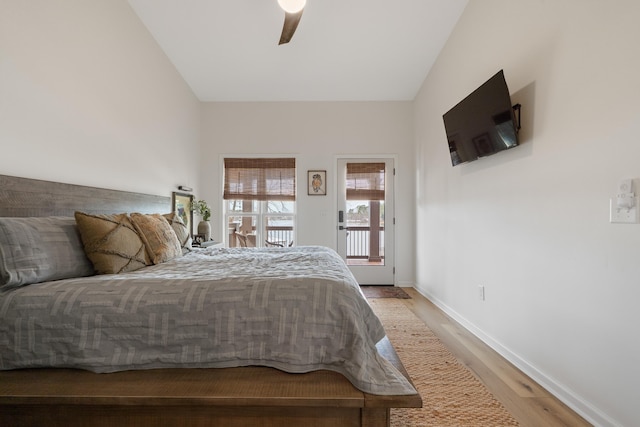 bedroom with baseboards, a ceiling fan, wood finished floors, access to exterior, and vaulted ceiling