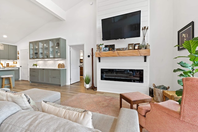 living area featuring a large fireplace, high vaulted ceiling, beam ceiling, and light wood-style floors