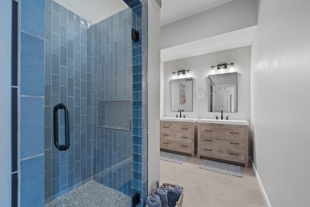 full bath featuring vanity, baseboards, a tile shower, and tile patterned floors