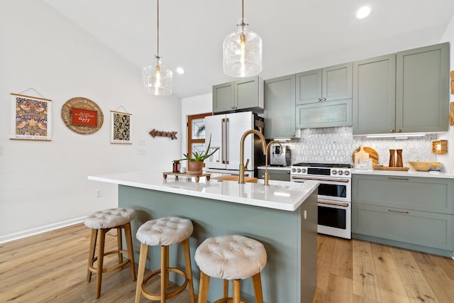 kitchen with hanging light fixtures, a kitchen island with sink, light countertops, a breakfast bar, and high end appliances