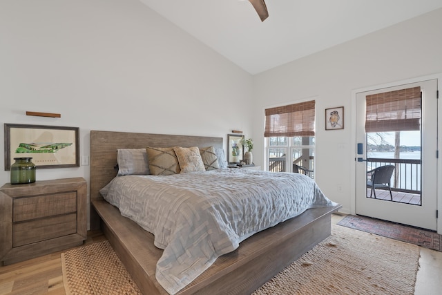 bedroom featuring access to exterior, multiple windows, lofted ceiling, and a water view