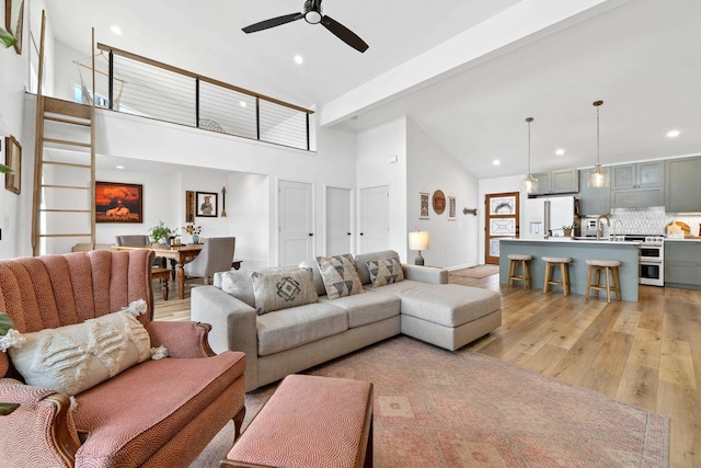 living room with high vaulted ceiling, recessed lighting, a ceiling fan, beam ceiling, and light wood finished floors