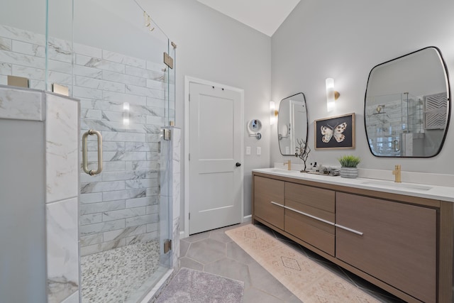 full bath with a sink, tile patterned floors, double vanity, and a stall shower