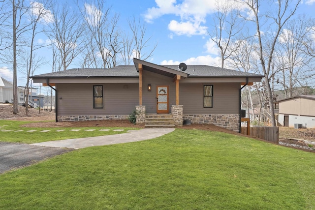 view of front facade with a front lawn, roof with shingles, and fence