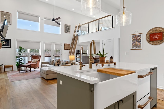 kitchen with light wood-style flooring, open floor plan, light countertops, a healthy amount of sunlight, and pendant lighting