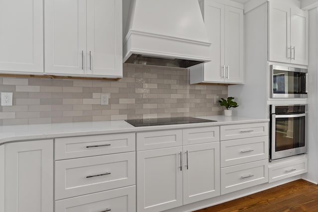 136 Hidden Lake Dr, Eatonton, GA 31024 - kitchen featuring black electric stovetop, premium range hood, stainless steel oven, white cabinets, and tasteful backsplash