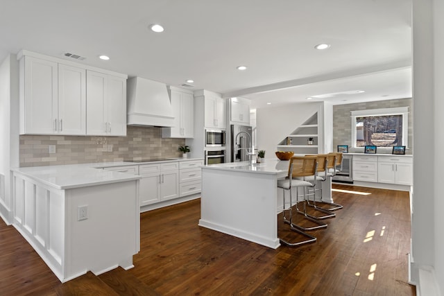 136 Hidden Lake Dr, Eatonton, GA 31024 - kitchen featuring dark wood-style flooring, custom exhaust hood, visible vents, appliances with stainless steel finishes, and beverage cooler