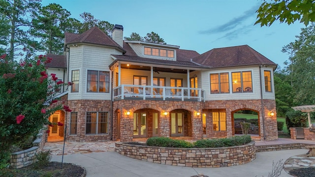 back house at dusk with a balcony and a patio area