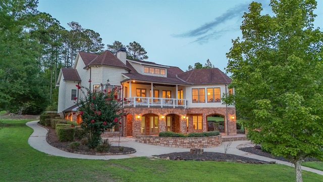 view of front of house featuring a balcony, a front yard, and ceiling fan