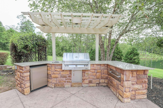 view of patio featuring a grill, a water view, and exterior kitchen