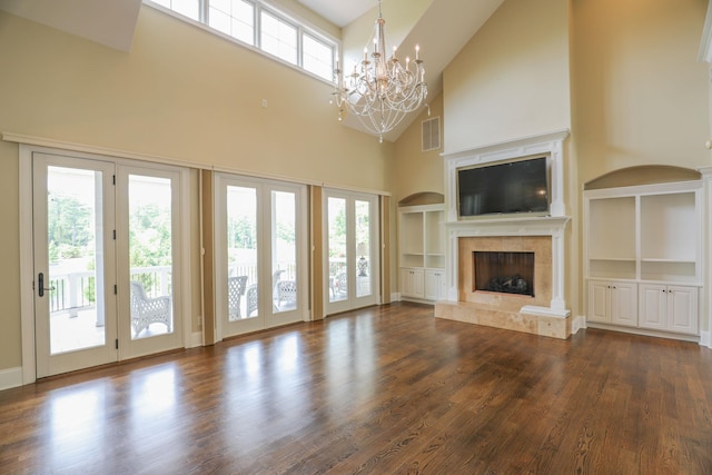 unfurnished living room with dark hardwood / wood-style floors, a chandelier, a high end fireplace, and built in shelves