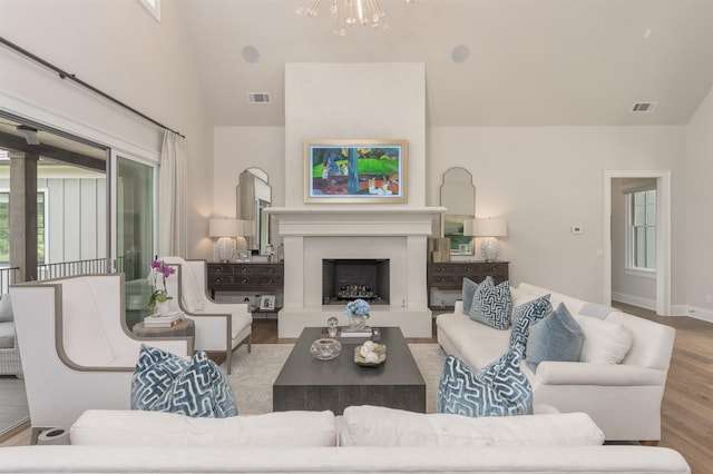1070 Griffin Crk, Greensboro, GA 30642 - living area featuring a chandelier, wood finished floors, a fireplace with raised hearth, and high vaulted ceiling