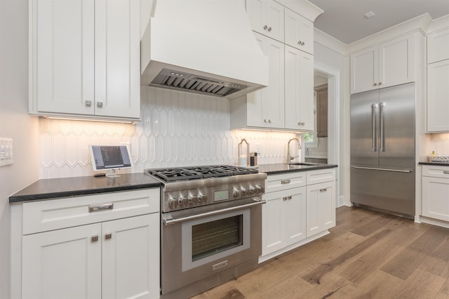 1070 Griffin Crk, Greensboro, GA 30642 - kitchen featuring high quality appliances, custom exhaust hood, dark countertops, light wood finished floors, and backsplash