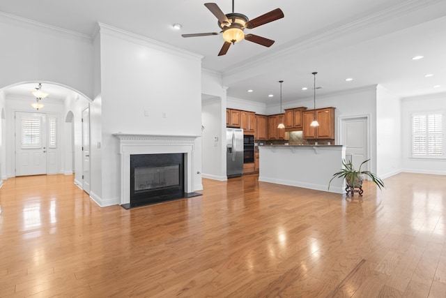 unfurnished living room featuring ceiling fan, crown molding, light hardwood / wood-style floors, and a healthy amount of sunlight