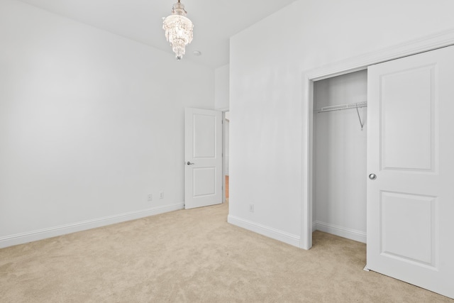 unfurnished bedroom with light colored carpet, an inviting chandelier, and a closet