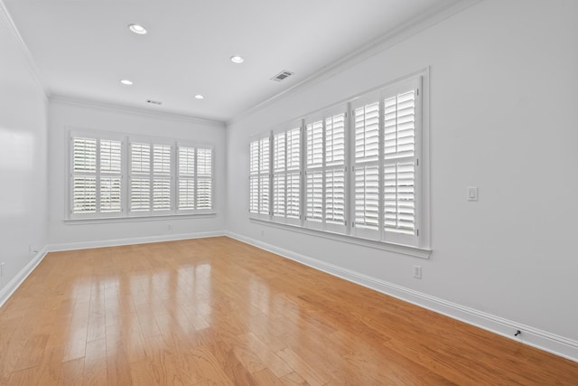 spare room featuring a healthy amount of sunlight, ornamental molding, and light hardwood / wood-style floors