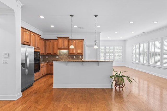 kitchen featuring a center island, decorative light fixtures, a breakfast bar, and black appliances