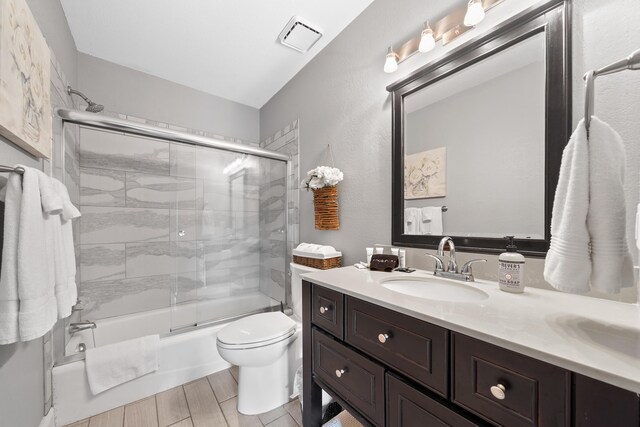 408 Sheffield Ln, Sparta, GA 31087 - full bathroom with visible vents, toilet, wood tiled floor, vanity, and shower / bath combination with glass door