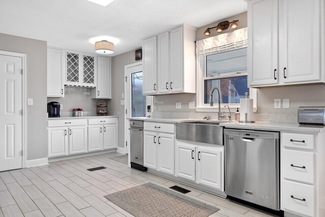 408 Sheffield Ln, Sparta, GA 31087 - kitchen with stainless steel dishwasher, wood finish floors, white cabinetry, a sink, and light countertops