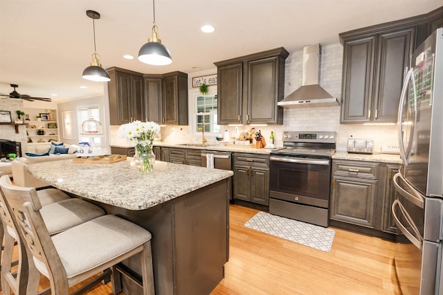 251 Pettigrew Rd, Milledgeville, GA 31061 - kitchen with light wood finished floors, ceiling fan, appliances with stainless steel finishes, open floor plan, and wall chimney range hood