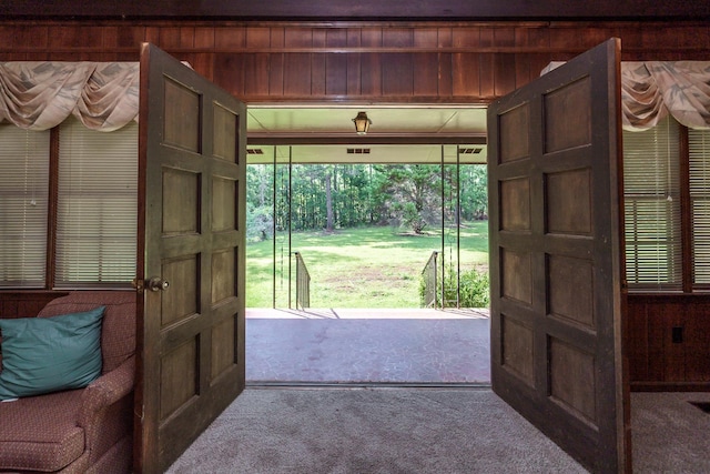 doorway featuring carpet floors and wood walls