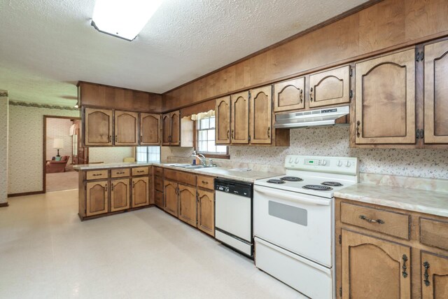 kitchen with sink, a textured ceiling, white appliances, and kitchen peninsula