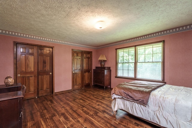 bedroom with dark hardwood / wood-style flooring, a textured ceiling, and two closets