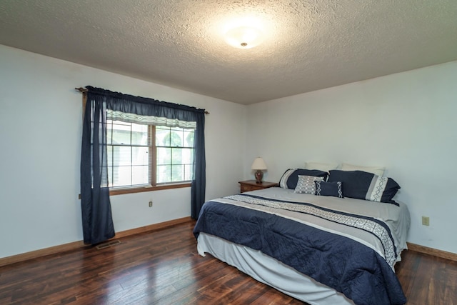 bedroom with dark hardwood / wood-style floors and a textured ceiling