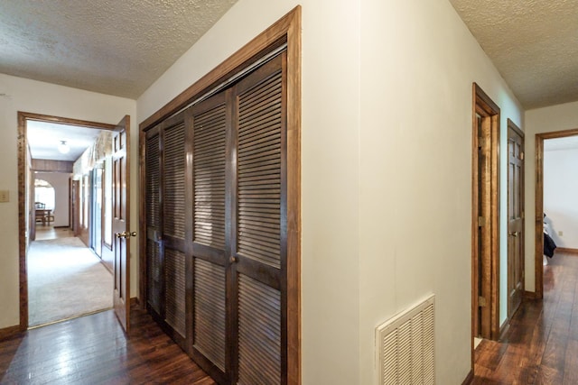 corridor with dark hardwood / wood-style floors and a textured ceiling