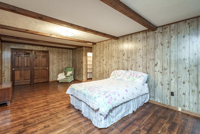 bedroom with beamed ceiling, dark wood-type flooring, and a textured ceiling