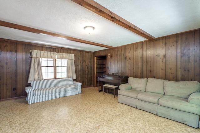 living room featuring wooden walls, a textured ceiling, and beam ceiling