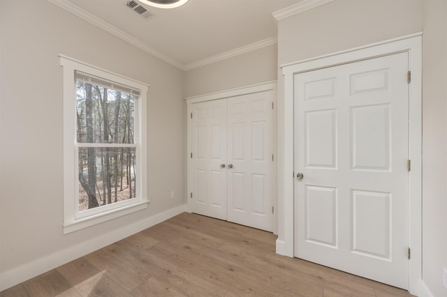 unfurnished bedroom featuring crown molding, a closet, and light wood-type flooring