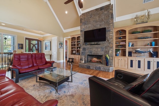 living room featuring ceiling fan, hardwood / wood-style floors, high vaulted ceiling, a fireplace, and ornamental molding