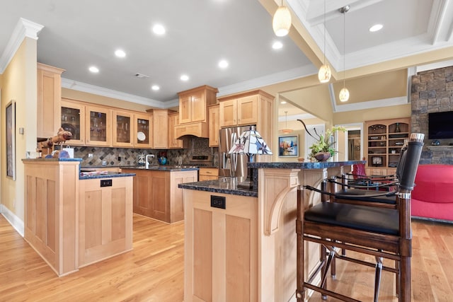 kitchen with pendant lighting, a kitchen breakfast bar, kitchen peninsula, light brown cabinets, and light hardwood / wood-style flooring