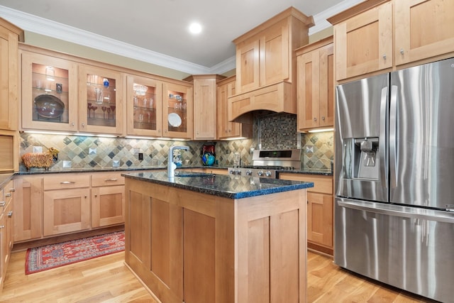 kitchen featuring stove, stainless steel refrigerator with ice dispenser, an island with sink, custom exhaust hood, and dark stone counters