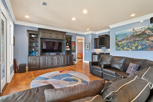 living room with ornamental molding, wet bar, and light hardwood / wood-style flooring